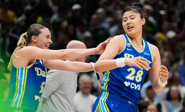 Dallas Wings guard Paige Bueckers, left, smiles while pushing center Li Yueru (28) after she made a basket against the Seattle Storm during the second half of a WNBA basketball game, Monday, June 22, 2026, in Seattle. (AP Photo/Lindsey Wasson)