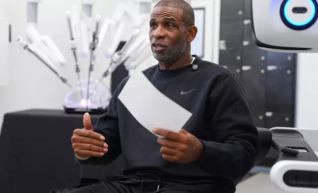 Colorado head football coach Deion Sanders talks after working the Da Vinci robotic surgical machine used to remove his cancerous bladder last year during a demonstration of the device Tuesday, June 23, 2026, in Boulder, Colo. (AP Photo/David Zalubowski)