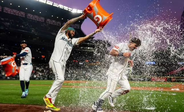 Seattle Mariners' J.P. Crawford, middle, and Julio Rodriguez, left, douse Cole Young with water after a baseball game against the New York Mets, Monday, June 1, 2026, in Seattle. (AP Photo/Stephen Brashear)