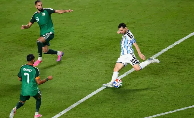 Argentina's Lionel Messi (10) shoots and scores their third goal against Algeria's Riyad Mahrez (7) and Nabil Bentaleb (19) during the World Cup Group J soccer match between Argentina and Algeria in Kansas City, Mo., Tuesday, June 16, 2026. (AP Photo/Reed Hoffmann)