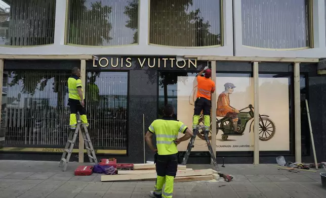 Construction workers board up a shop window, ahead of expected protests for the G7 summit, in Geneva, Switzerland, Monday, June 8, 2026. (AP Photo/Baz Ratner)
