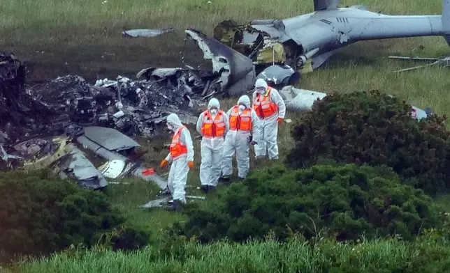 Inspectors at the scene a day after a Royal Navy helicopter crashed in a field, in Sourton Down, near Okehampton in Devon, England, Thursday, June 4, 2026, (PA via AP)