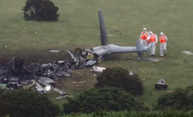 Inspectors at the scene a day after a Royal Navy helicopter crashed in a field, in Sourton Down, near Okehampton in Devon, England, Thursday, June 4, 2026, (PA via AP)