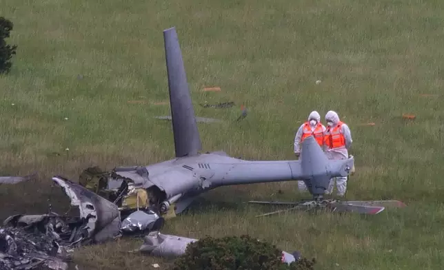 Inspectors at the scene a day after a Royal Navy helicopter crashed in a field, in Sourton Down, near Okehampton in Devon, England, Thursday, June 4, 2026, (PA via AP)