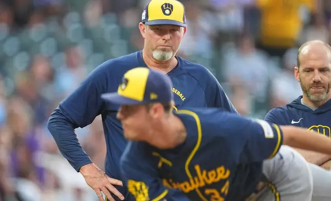 Milwaukee Brewers pitching coach Chris Hook, top left, looks on as starter Jacob Misiorowski, foreground, throws a practice pitch after being hit by a single off the bat of Colorado Rockies' Troy Johnston in the second inning of a baseball game Saturday, June 6, 2026, in Denver. (AP Photo/David Zalubowski)