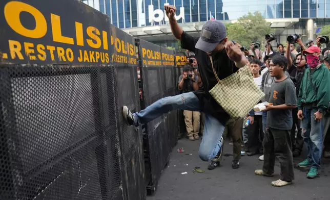 A student protester kicks a police barricade during a rally against a fuel price hike, government inefficient spendings, and military involvement in civilian affairs in Jakarta, Indonesia, Friday, June 12, 2026. (AP Photo/Dita Alangkara)