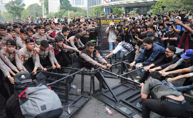 Student protesters tear down a police barricade during a rally against a fuel price hike, government inefficient spendings, and military involvement in civilian affairs in Jakarta, Indonesia, Friday, June 12, 2026. (AP Photo/Dita Alangkara)