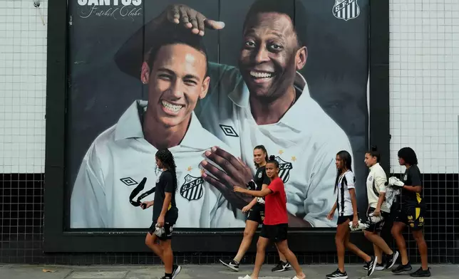 Santos fans walk past a mural of late football legend Pele, right, and Neymar outside Vila Belmiro Stadium in Santos, Brazil, Thursday, May 28, 2026. (AP Photo/Andre Penner)
