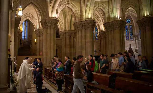 Worshippers receive communion during a Mass in the crypt of the Sagrada Familia in Barcelona, Spain, on Friday, May 15, 2026. (AP Photo/Emilio Morenatti)