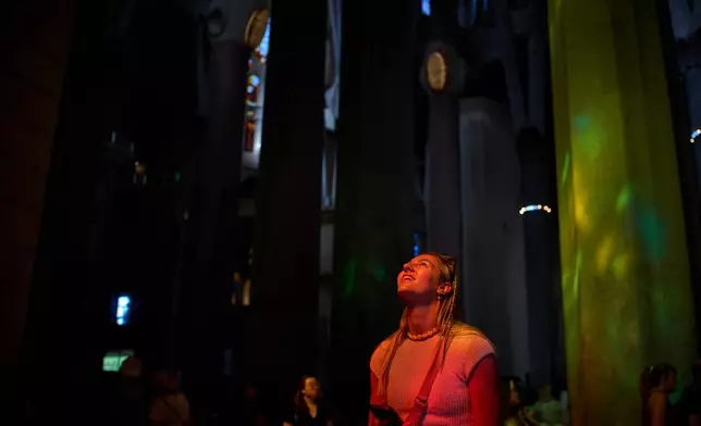 A visitor, bathed in sunlight streaming through the stained-glass windows, gazes up at the ceiling of the Sagrada Familia in Barcelona, Spain, Tuesday, May 26, 2026. (AP Photo/Emilio Morenatti)