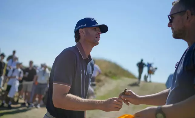 Marcus Plunkett of the United States signs an autograph for a fan between the 12th and 13th holes during a practice round for the British Open Golf championships at Royal Birkdale golf club, in Southport, England, Tuesday, July 14, 2026. (AP Photo/David Goldman)