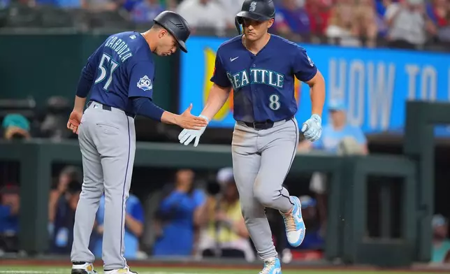 Seattle Mariners designated hitter Dominic Canzone (8) is congratulated by third base coach Carlos Cardoza, left, after hitting a home run during the seventh inning of a baseball game against the Texas Rangers, Sunday, July 26, 2026, in Arlington, Texas. (AP Photo/LM Otero)