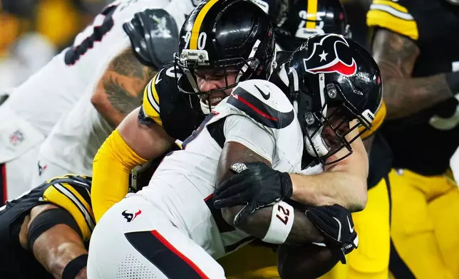 FILE - Houston Texans running back Woody Marks (27) is tackled by Pittsburgh Steelers linebacker T.J. Watt (90) during the first half of NFL wild-card playoff football game, Jan. 12, 2026, in Pittsburgh. (AP Photo/Gene J. Puskar, File)