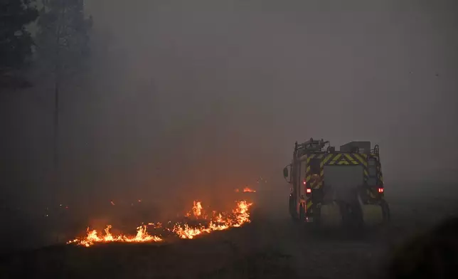 A fire engine drives through smoke of a wildfire raging near Marcheprime, outside, Bordeaux, France, Sunday, July 26, 2026. (AP Photo/Emma Da Silva)