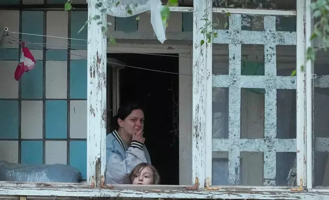 Local residents look out of the balcony at a building damaged by Russian missile attack in Kyiv, Ukraine, Monday, July 6, 2026. (AP Photo/Efrem Lukatsky)
