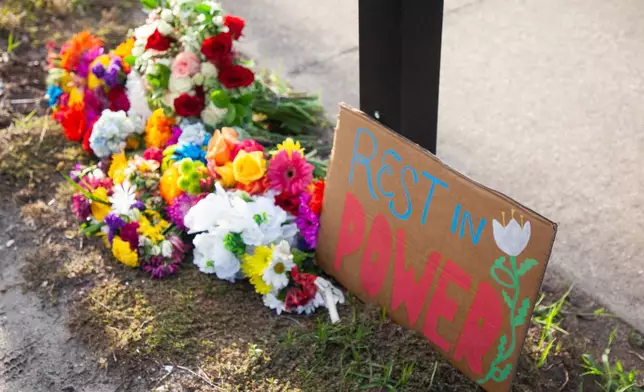 A sign reading "rest in power" is displayed alongside flowers at a vigil for a Mexican man who was struck and killed by a tractor trailer while running from an encounter with Immigration and Customs Enforcements officers the day before, Wednesday, July 15, 2026, in St. Augustine, Fla. (AP Photo/Kelly Jordan)