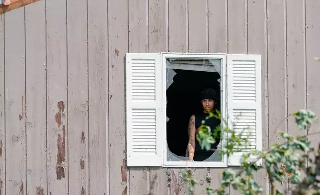 Alex Leon looks through a broken window after a tornado hit the day before, Tuesday, July 28, 2026, in Menasha, Wis. (AP Photo/Kayla Wolf)