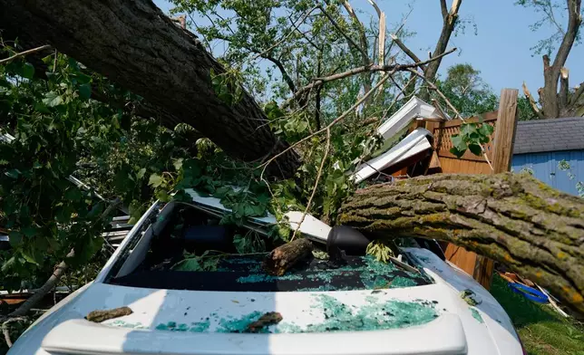 A car sits crushed beneath a fallen tree after a tornado tore through a day before in Appleton, Wis., Tuesday, July 28, 2026. (AP Photo/Kayla Wolf)
