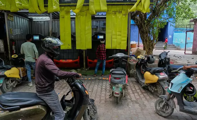 Delivery workers and drivers arrive at a battery-swapping station for electric vehicles in New Delhi, India, Monday, July 13, 2026. (AP Photo/Manish Swarup)