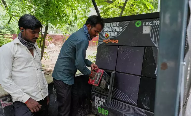 A person swaps their electric scooter battery at a battery-swapping station for electric vehicles in New Delhi, India, Monday, July 13, 2026. (AP Photo/Manish Swarup)