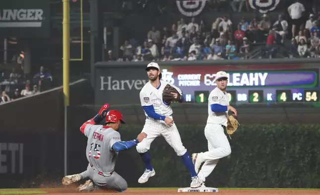 Chicago Cubs shortstop Dansby Swanson, center, throws to first base to complete a double play after forcing out St. Louis Cardinals José Fermín, left, at second base during the fourth inning of a baseball game Saturday, July 4, 2026, in Chicago. (AP Photo/David Banks)