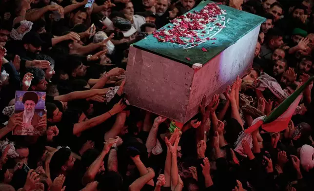 The flower petal-covered coffin of the late Iranian Supreme Leader Ayatollah Ali Khamenei is carried above mourners reaching out to touch it outside the Imam Hussein Shrine in Karbala, Iraq, early Thursday, July 9, 2026. (AP Photo/Khalil Hamra)