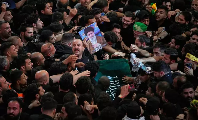 The coffin of the late Iranian Supreme Leader Ayatollah Ali Khamenei is carried through a tightly packed crowd as mourners jostle to reach and touch it outside the Imam Hussein Shrine in Karbala, Iraq, early Thursday, July 9, 2026. (AP Photo/Khalil Hamra)