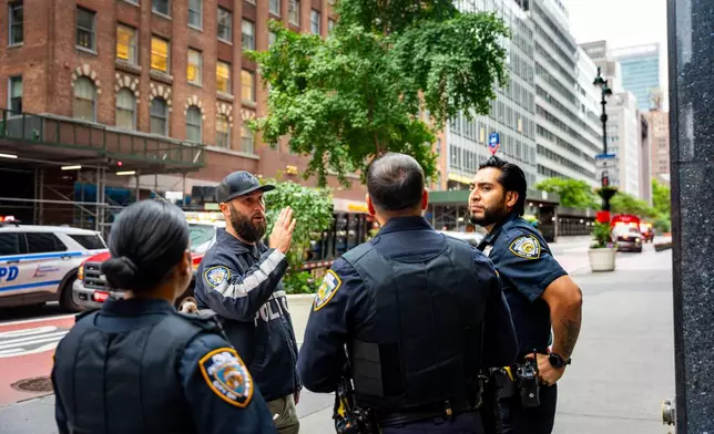 NYPD officers talk about nearby buildings that were evacuated, Tuesday, July 7, 2026, in New York. (AP Photo/Angelina Katsanis)