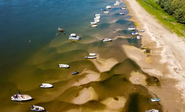 Boats sit on a bank of the Danube River where usually submerged areas are exposed due to extremely low water levels following an extended period of drought in Islaz, Romania, Wednesday, July 29, 2026. (AP Photo/Nicolae Dumitrache)