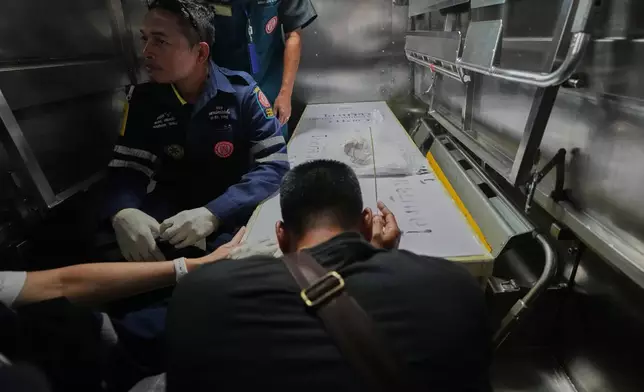 A relative of a victim in a music bar fire pays respect to the victim's body at a police hospital in Bangkok, Thailand, Tuesday, July 14, 2026. (AP Photo/Sakchai Lalit)