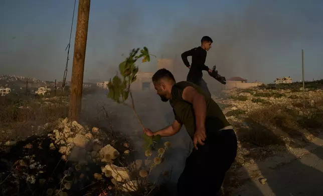 Palestinians extinguish a small fire after Israeli forces fired tear gas during a raid in the village of Sarra, near the West Bank city of Nablus, Saturday, July 25, 2026. (AP Photo/Leo Correa)