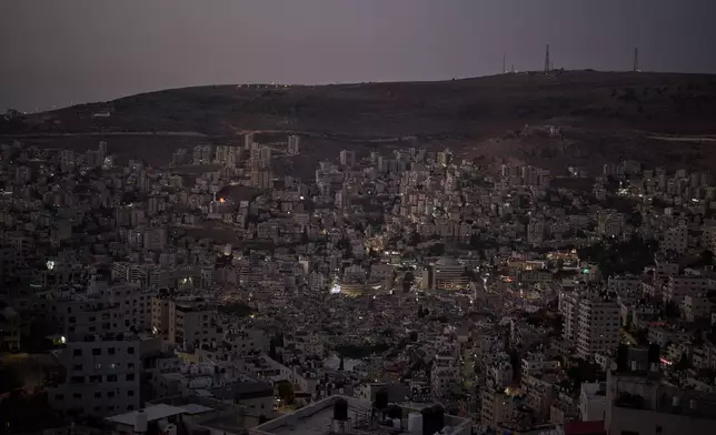 Buildings stand in a valley at dusk in the West Bank city of Nablus, Saturday, July 25, 2026. (AP Photo/Leo Correa)