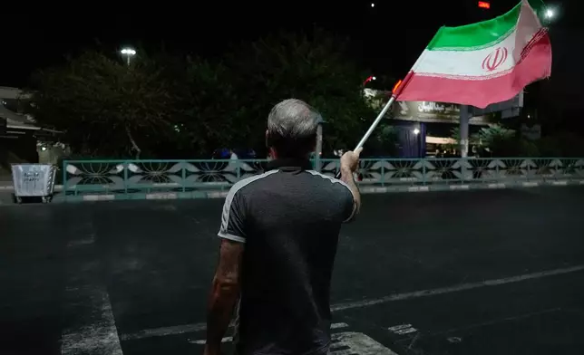 A pro-government demonstrator waves an Iranian flag in a gathering commemorating the late Iranian Supreme Leader Ayatollah Ali Khamenei at a square in Tehran, Iran, Saturday, July 11, 2026. (AP Photo/Vahid Salemi)