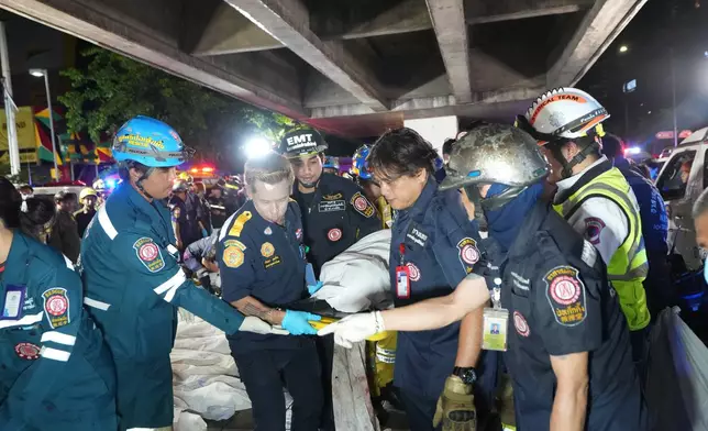 Rescuers carry the body of a victim of a fire in Bangkok, Thailand, Monday, July 13, 2026. (AP Photo/Sakchai Lalit)