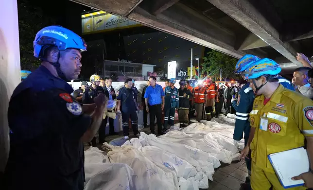 Thailand Prime Minister Anutin Charnvirakul, in blue, inspects the site of a fire as bodies of victims are laid in a row in Bangkok, Thailand, Monday, July 13, 2026. (AP Photo/Sakchai Lalit)