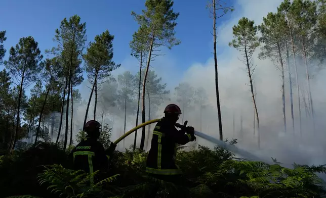 Firefighters work to suppress a fire near Lacanau, as wildfires rage outside Bordeaux, France, Monday, July 27, 2026. (AP Photo/Baz Ratner)