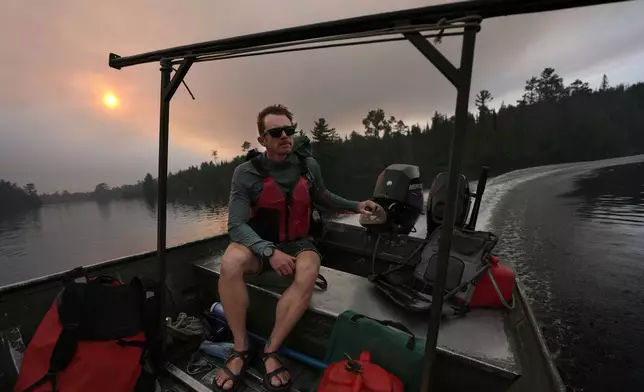 Willy Vosburgh, owner of Vosburgh's Custom Cabin Rentals on Moose Lake, uses a tow boat to evacuate canoeists from the Boundary Waters Canoe Area Wilderness after multiple wildfires burning there prompted its closure and evacuation Tuesday, July 14, 2026 in Ely, Minn. (Anthony Souffle/Minnesota Star Tribune via AP)