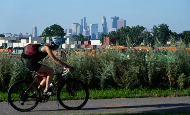 A cyclist passes the Minneapolis skyline along St. Anthony Parkway as smoke from wildfires in Canada and Northern Minnesota sets in, Wednesday, July 15, 2026. (AP Photo/Ellen Schmidt)