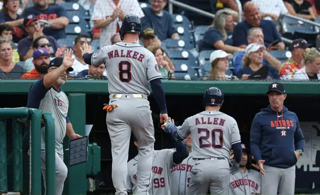Houston Astros' Christian Walker (8) is greeted in the dugout after scoring a run on a sacrifice fly hit by Nick Allen (20) hit off Washington Nationals pitcher Andrew Alvarez during the second inning of a baseball game, Tuesday, July 7, 2026, in Washington. (AP Photo/Terrance Williams)
