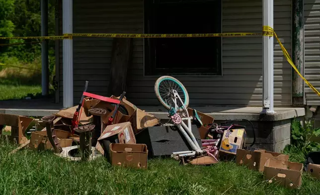 Police tape and debris are seen at a home where authorities say they removed 16 children and arrested four adults in Hamden, Ohio, Wednesday, July 1, 2026. (AP Photo/Carolyn Kaster)