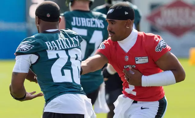 Philadelphia Eagles quarterback Jalen Hurts (1) hands the ball off to running back Saquon Barkley (26) during practice at the team's NFL football training camp in Philadelphia, Wednesday, July 29, 2026. (AP Photo/Chris Szagola)