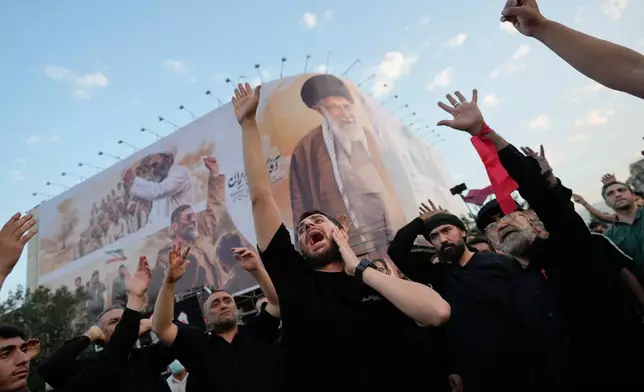 Mourners chant slogans while gathered in Islamic Revolution Square for the funeral procession of the slain Iranian Supreme Leader Ayatollah Ali Khamenei beneath a billboard depicting Khamenei in Tehran, Iran, Monday, July 6, 2026. (AP Photo/Altaf Qadri)