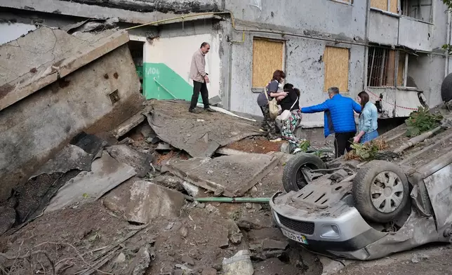 Local residents walk amid debris following a Russian missile attack in Kyiv, Ukraine, Monday, July 6, 2026. (AP Photo/Efrem Lukatsky)