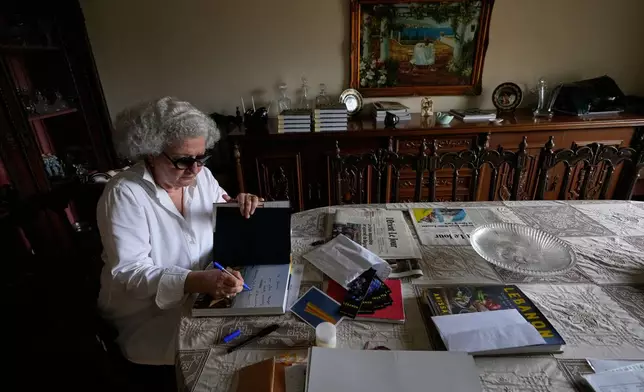 Anissa Helou, 74, one of the Middle East's most acclaimed cooks and food writers, signs a copy of her new book at her late mother's apartment in the Mount Lebanon town of Ballouneh, Thursday, July 2, 2026. (AP Photo/Hussein Malla)