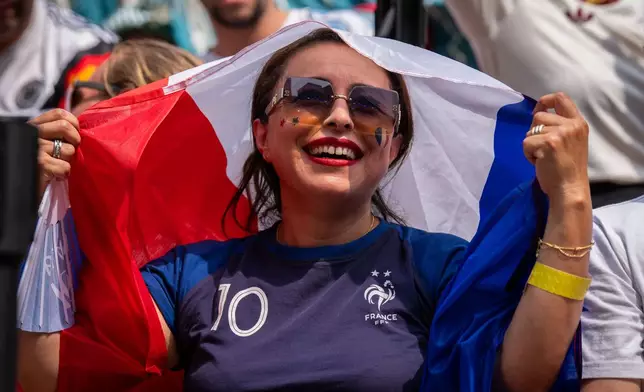 A French fan shields themselves from the sun during the World Cup semifinal soccer match between Spain and France at a watch party at the Rockefeller Center fan village, Tuesday, July 14, 2026, in New York. (AP Photo/Adam Gray)