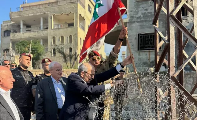 In this photo released by the Lebanese Government press office, Lebanese Prime Minister Nawaf Salam, center, raises a Lebanese flag during a visit to the southern village of Zawtar Al Gharbieh, Lebanon, Wednesday, July 22, 2026. (Lebanese Government press office via AP)