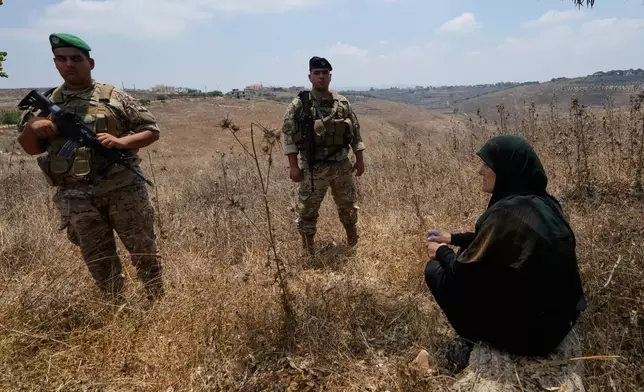 Lebanese army soldiers stand near a woman after preventing her from entering the southern village of Zawtar Al Gharbieh, Lebanon, Wednesday, July 22, 2026. (AP Photo/Mohammed Zaatari)