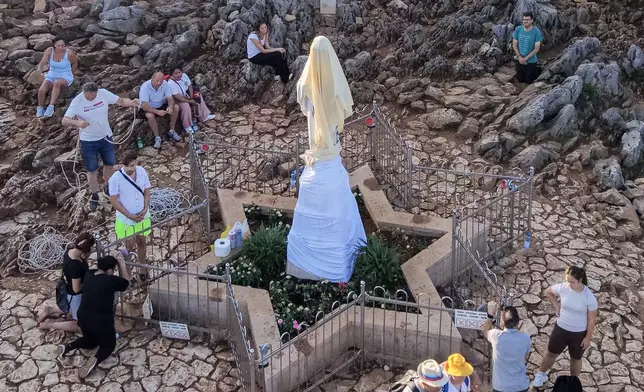 An aerial view of pilgrims praying next to the vandalized statue of the Virgin Mary, which has been covered with a white sheet, on Apparition Hill in Medjugorje, Bosnia, Tuesday, July 28, 2026. (AP Photo)