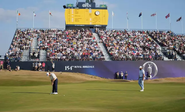 Tommy Fleetwood of England, left putts on the 18th green, watched by Jon Rahm of Spain, during the third day of the British Open Golf championships at Royal Birkdale golf club, in Southport, England, Saturday, July 18, 2026. (AP Photo/Jon Super)