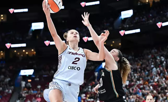 Toronto Tempo's Laura Juskaite (2) goes up for a basket as New York Liberty's Sabrina Ionescu, second from left, defends during the first half of a WNBA basketball game in Montreal, Sunday, July 12, 2026. (Graham Hughes/The Canadian Press via AP)